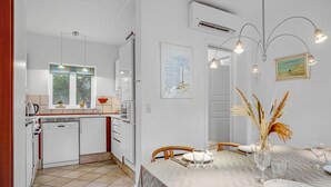A modern kitchen with white cabinets, a window, and a dining area with a table set for two. - 3 bedroom nice home in Blåvand (Blåvand)