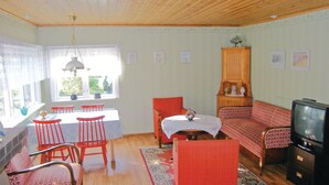 En hyggelig stue med spiseplads, træloft og et fjernsyn.