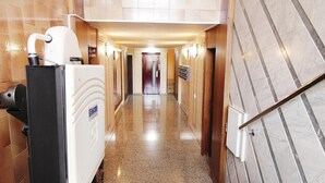 Un pasillo de hotel con un secador de manos, un letrero con un número de habitación y una puerta al final.
