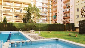 Una piscina con escalones de acceso, rodeada de un césped cuidado y un seto.