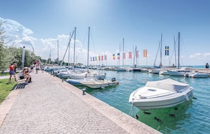 A marina with boats docked, a paved walkway, and people sitting on benches. - 2 bedroom stunning apartment in Lazise -VR- (Lazise -VR-)