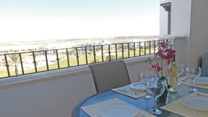 Une table à manger dressée pour deux personnes, avec vue sur un paysage côtier.