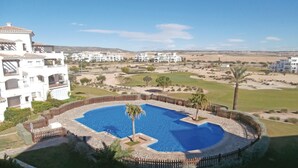 Une piscine entourée d’une terrasse en pierre, avec en arrière-plan une vue sur un quartier résidentiel.