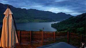 A wooden deck with a table and an umbrella, overlooking a lake and mountains. - Amazing home in Etne with WiFi (Etne)