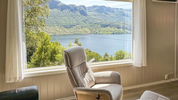 A room with a view of a lake and mountains, a chair, and a small table. - Amazing home in Etne with WiFi (Etne)
