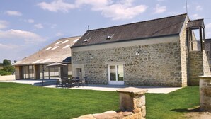 Un bâtiment en pierre avec un toit en pente, une porte et une petite fenêtre.