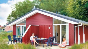 Eine rote Holzhütte mit überdachter Terrasse, einem Esstisch und Stühlen.