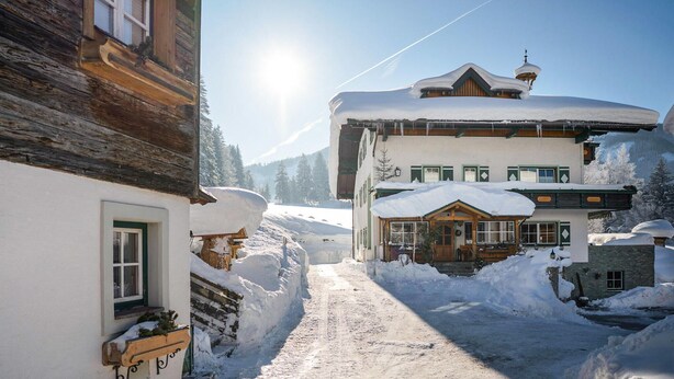 A snow-covered village with traditional wooden buildings, a clear sky, and a visible mountain in the background. - sehr schoene Ferienwohnung (Schladming)
