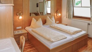 A double bed with a wooden headboard and footboard, two bedside tables, a nightstand, a mirror, and a window with curtains. - sehr schoene Ferienwohnung (Schladming)