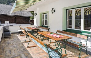 An outdoor dining area with wooden benches and tables, a grill, and a view of the surrounding landscape. - sehr schoene Ferienwohnung (Schladming)