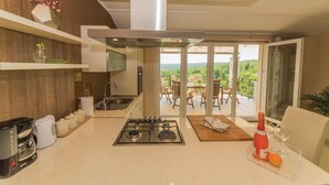 Eine moderne Küche mit Gasherd, Spüle und Blick auf einen Balkon mit Gartenmöbeln.
