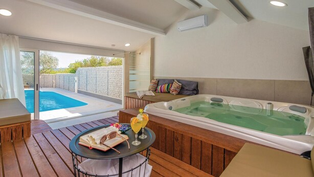 Ein Zimmer mit Holzterrasse, Whirlpool und Glastür zum Schwimmbad.