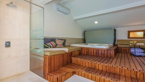 Ein kleiner, gemütlicher Raum mit einer hölzernen Bank, einem Bett, einer Dusche und einem Fenster.
