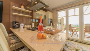 Eine moderne Küche mit einer großen Kochinsel, einer Champagnerflasche und einem schönen Balkonblick.