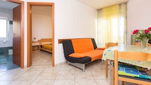 A compact living space with a sofa, a dining table, and a small kitchen area.