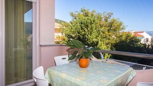 A balcony with a table, chairs, and a potted plant.