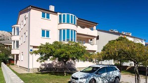 A multi-story residential building with a curved facade, numbered 40, and a parked car in front.