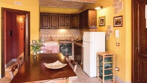 Une cuisine de taille réduite, dotée de meubles en bois, d’une cuisinière à gaz, d’un réfrigérateur blanc et d’une table à manger avec des chaises.