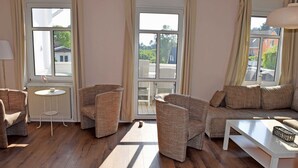 A furnished living room with a sofa, armchairs, a coffee table, and a small side table. - Vacation Rental in the Baltic Sea Resort of Göhren (01) - Vacation Rental with a Balcony (01) (Göhren)