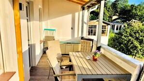 A covered patio area with a wooden table and chairs, a potted plant, and a view of the surrounding greenery. - Vacation Rental in the Baltic Sea Resort of Göhren (01) - Vacation Rental with a Balcony (01) (Göhren)