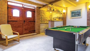 Een biljarttafel, een houten stoel en een bakstenen muur met een open haard.