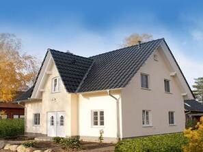 Et tosset hus med saddeltag, en fordør og en lille forhave.