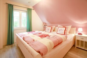 A bedroom with a bed, a nightstand, a window with curtains, and a lamp.