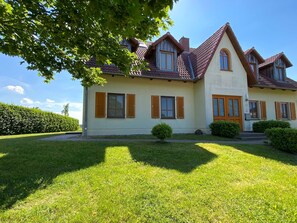 A two-story house with a sloped roof, wooden shutters, and a well-maintained lawn.