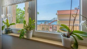 Ein Fenster mit Topfpflanzen und Blick auf ein Gebäude mit rotem Dach und einer Treppe.