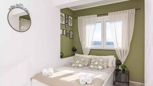 Ein ordentlich eingerichtetes Schlafzimmer mit einem Bett, einem Nachttisch, einem Spiegel und einem Fenster mit Vorhängen.