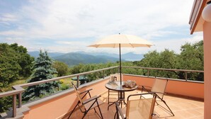 A balcony with a table, chairs, and a table set for tea, overlooking a mountainous landscape. - Amazing home in Acquavena di R. (SA) (Acquavena di R. (SA))