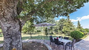 An outdoor patio with a table and chairs, surrounded by trees and a well-maintained lawn. - Cozy home in Labin with kitchen (Labin)