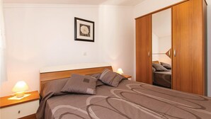 A bedroom with a bed, a nightstand with a lamp, a wardrobe, and a framed picture on the wall. - Cozy home in Labin with kitchen (Labin)