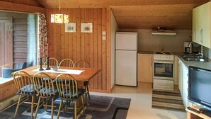 A compact kitchen with a dining area, wooden walls, a refrigerator, stove, and a television. - Gorgeous home in Olden with house a mountain view (Olden)