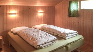 A wooden cabin room with two beds, a nightstand, and two wall-mounted lights. - Gorgeous home in Olden with house a mountain view (Olden)