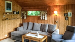 A cozy living room with a sectional sofa, a wooden coffee table, a blue armchair, and a window with curtains. - Gorgeous home in Olden with house a mountain view (Olden)