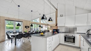 A modern kitchen with white cabinets, a central island, and a dining area with black chairs and a wooden table. - Gorgeous home in Sydals with sauna (Sydals)