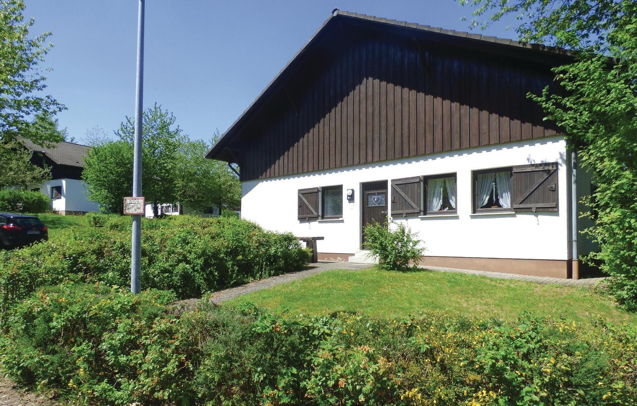 A white building with a brown roof, surrounded by greenery and a clear sky.