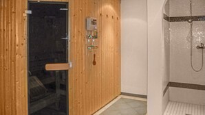 A sauna room with a wooden door, a glass door, and a shower area with a tiled floor. - Ferienwohnung in Ischgl (Ischgl)