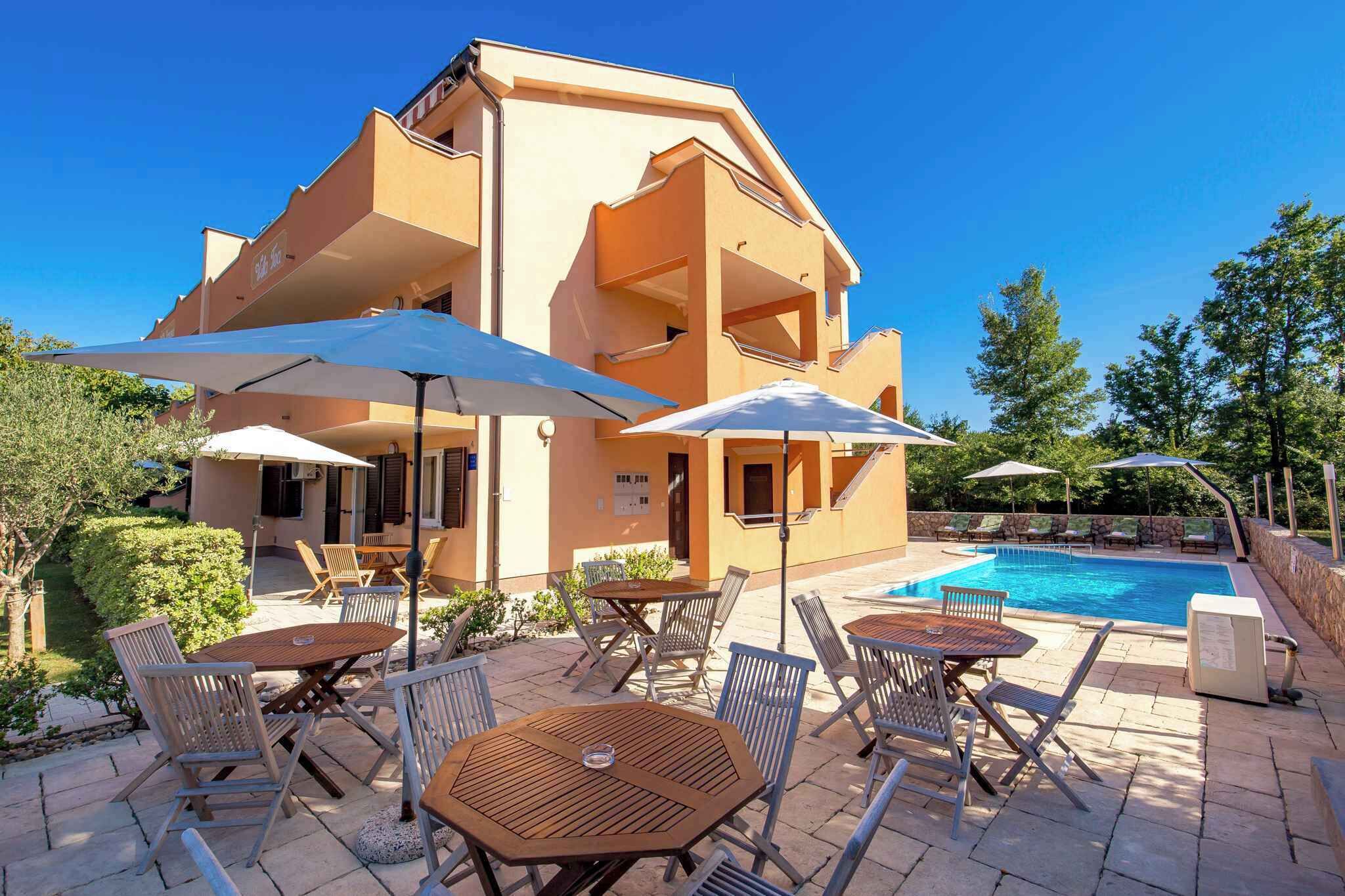 A multi-story building with a swimming pool, outdoor seating, and umbrellas.