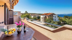 A balcony with a wooden table, a bowl of fruit, and a vase of flowers. - Holiday apartment with air conditioning and pool (����ilo)