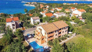 A coastal residential area with a large building featuring a swimming pool and a view of the sea. - Holiday apartment with air conditioning and pool (����ilo)