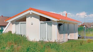 Un petit bâtiment d’un seul étage, doté d’un toit recouvert de tuiles rouges et de murs blancs, entouré de verdure.