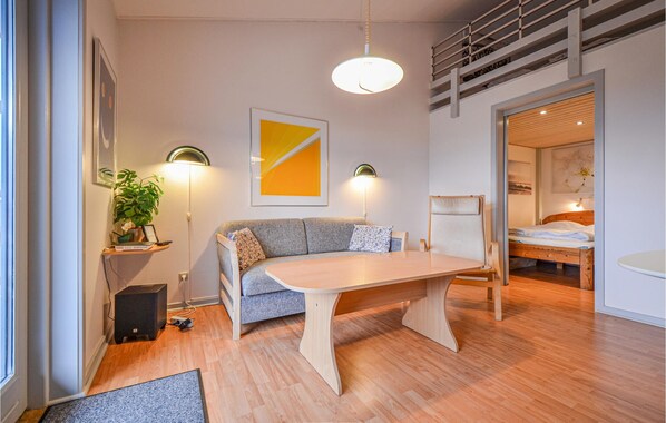 Una sala moderna con un sofá, una mesa de madera y una cama al fondo.