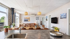 A modern kitchen with a central island, stainless steel sink, and a dining area with brown leather sofas. - Stunning home in Haderslev with WiFi (Haderslev)