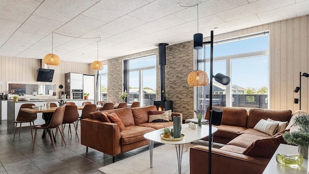 A modern living room with a fireplace, leather sofas, and a dining area with a large window. - Stunning home in Haderslev with WiFi (Haderslev)