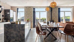 A modern kitchen with a central island, large windows, and a dining area with chairs and a table. - Stunning home in Haderslev with WiFi (Haderslev)