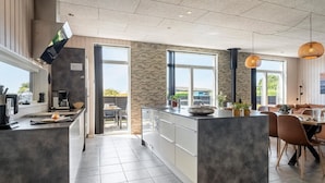 A modern kitchen with a large island, a dining area with a table and chairs, and a view of the outdoors. - Stunning home in Haderslev with WiFi (Haderslev)