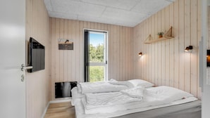 A bedroom with a bed, a TV, a window, and a wooden wall. - Stunning home in Haderslev with WiFi (Haderslev)