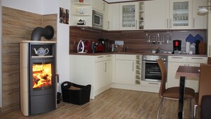Une cuisine équipée d’un poêle à bois, d’un four à micro-ondes, d’un four traditionnel et de divers ustensiles de cuisine.